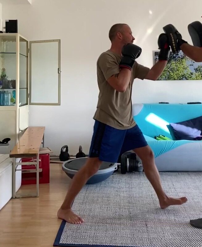 Florian Schwab beim Boxtraining in seinem Fitnessstudio: im Ausfallschritt, Boxhandschuhe oben, er trainiert an den Pratzen.